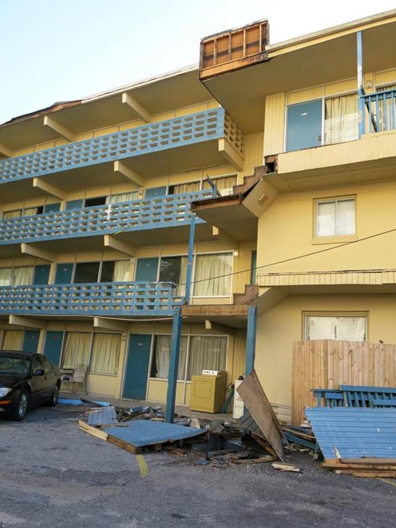 Wind damage to motel roof, balcony, and stairwell walls