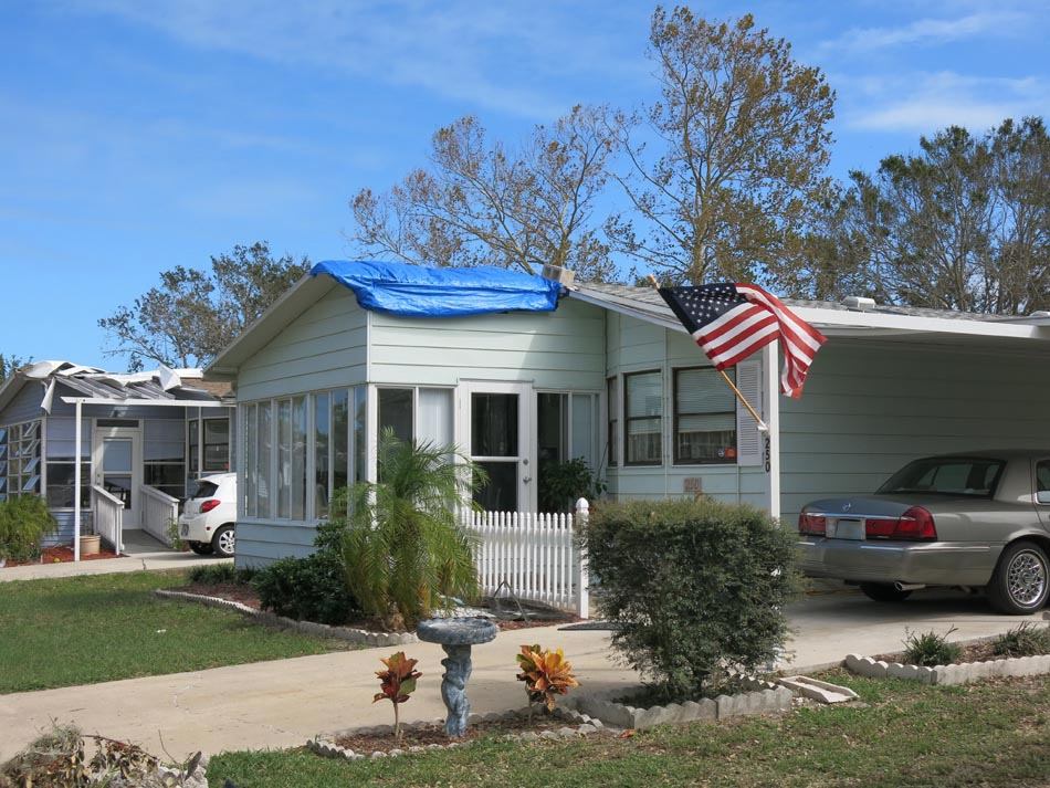 Carport and overhang failure, which has been tarped to prevent further loss; in the background there is roof cover failure.